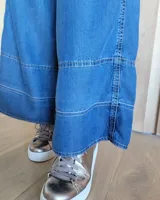 Pantalón de jean azul de corte palazzo con cintura alta y detalle de costuras horizontales en el ruedo.