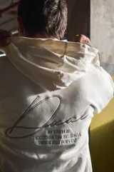 Hoodie canguro blanco de diseño oversize, con capucha, bolsillo frontal tipo koozban y sutil bordado monocromático en el pecho.