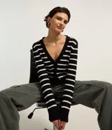 Cardigan corto de punto con diseño a rayas horizontales en blanco y negro. Presenta cuello en V, cierre frontal con botones y mangas largas.