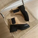 Botas chelsea bicolores con cuerpo de cuero beige, elásticos laterales negros, suela chunky negra con plataforma dentada y puntera con textura símil serpiente.