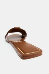 Sandalia plana dorada de piel con tiras cruzadas en la parte delantera.