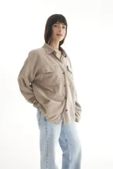 Camisa negra de pana, corte oversize, con cuello camisero, cierre frontal con botones, dos bolsillos con solapa en el pecho y mangas largas con puños abotonados.