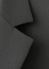 Blazer de corte recto y diseño crop, con cuello de solapa con muesca, cierre frontal de gancho y mangas largas con puños abotonados. Cuenta con bolsillos de ribete frontales y en el pecho, y forro interior.