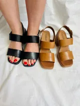 Sandalias negras de cuero con dos tiras anchas sobre el empeine, pulsera con hebilla al tobillo, taco cuadrado de 8 cm y plataforma delantera de 2,5 cm.