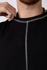 Musculosa oversize de algodón estilo sudadera, color crudo, con costuras visibles en contraste en color negro que recorren el centro verticalmente y enmarcan el cuello y el ruedo.