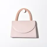 Cartera bandolera color rosa con asa superior de cuentas y solapa con cierre magnético.