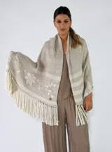 Pashmina de tejido de punto color beige con detalles bordados de flores en los bordes y flecos largos en tono crudo.