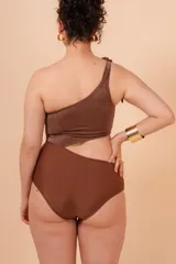 Malla entera marrón de un hombro con detalle de nudo y abertura lateral. Confeccionada en lycra con efecto lurex.