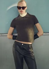 Jersey de punto grueso con cuello polo y cierre frontal de dos botones. Presenta un diseño corto de corte recto y mangas cortas.