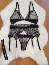 Conjunto de lencería compuesto por bralette triangular y bombacha tipo colaless, confeccionados en microtul estampado con detalles de encaje negro. Incluye portaligas desmontable con tiras ajustables.