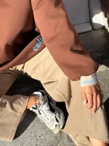 Buzo marrón de algodón, corte holgado, con cuello redondo y puños ajustados.