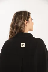 Camisa negra oversize de manga larga con cuello camisero y cierre frontal con botones.