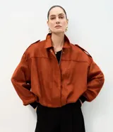 Campera bomber de gamuza sintética color terracota, con cuello clásico, cierre frontal, hombros caídos y puños ajustados.