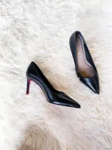 Zapatos de tacón alto con textura de reptil, color negro, con suela roja característica.