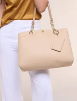 Cartera de hombro de cuero sintético beige, con estructura tripartita de compartimento central con cierre y dos compartimentos laterales con broche magnético. Posee asas dobles con detalles de cadena metálica dorada y un tarjetero independiente desmontable.
