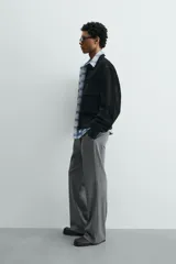 Cazadora cropped fit de piel con acabado serraje y textura de ante, color negro. Presenta cuello camisero, cierre frontal con cremallera, bolsillos delanteros de plastrón con solapa en el pecho y acabado de rib elástico en los puños y el bajo.