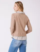 Buzo de punto fino color beige con diseño de camisa incorporada. Presenta escote en V con cierre frontal de botones, mangas largas con puños acanalados y cuello y ruedo con estampado de rayas verticales que simulan una camisa debajo.