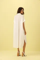 Vestido camisero blanco con botones y corte asimétrico.