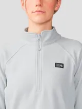 Polar de mujer Mountain Hardwear modelo Microchill 1/4 Zip, color gris, de manga larga raglán, cuello alto con cierre frontal parcial y pequeño logo bordado en el pecho.