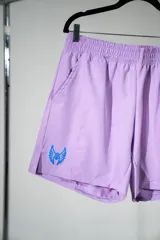 Short deportivo lila con cintura elástica, bolsillos laterales y logo estampado en azul en la pierna izquierda.