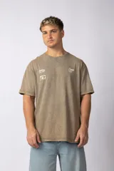 Remera de algodón con efecto lavado gastado en color marrón, de corte holgado y manga corta. Presenta estampados gráficos pequeños en el frente y un diseño grande en la espalda.