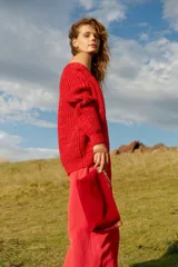 Sobre de mano rojo de gamuza con cierre de cremallera y correa de cuero marrón.