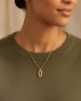 Collar de acero con baño de oro, con cadena de eslabones finos y dije colgante de diseño ovalado adornado con circonias en su contorno.