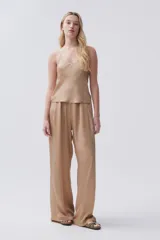 Pantalón palazzo color beige de viscosa, tiro alto, con bolsillos laterales y pinzas en el frente.