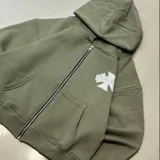 Campera con capucha color verde militar, con cierre frontal completo, bolsillos frontales estilo canguro y estampado gráfico en el pecho.