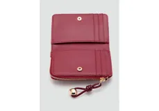 Billetera pequeña de diseño compacto en acabado charol color bordó. Cuenta con cierre perimetral con tirador decorativo de cordón y detalle metálico dorado, y logo de la marca grabado en el frente.