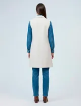 Chaleco largo tejido color blanco de la marca Sioni, con cuello solapa, doble botonadura dorada en el frente y bolsillos aplicados.