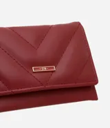 Billetera pequeña color bordó, con textura capitoneada y cierre a presión.