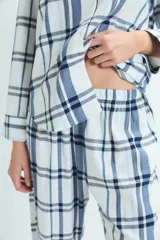 Pijama de dos piezas con estampado de cuadros en tonos azules y blancos. La parte superior es una camisa de manga larga con cuello camisero y cierre frontal de botones. La parte inferior es un pantalón de corte recto con cintura elástica.