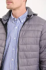 Campera capitoneada color azul marino, con capucha de algodón gris desmontable y cierre frontal. Tiene dos bolsillos exteriores con cierre.