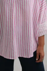 Blusa de corte holgado con estampado de rayas verticales en color fucsia y blanco. Presenta cuello camisero con escote en V y mangas largas con puños vueltos.