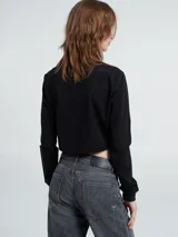 Camiseta blanca de manga larga y cuello redondo, con corte cropped y logo bordado en el pecho.