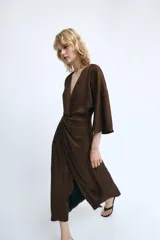 Vestido midi de tejido satinado color marrón, con escote en pico, manga corta y detalle de nudo frontal que genera un efecto drapeado.