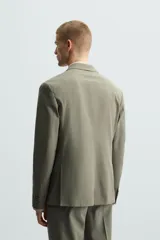 Blazer de corte regular fit confeccionado en tejido con lana, con cuello de solapas de muesca, cierre frontal de un botón, bolsillos de solapa en la cadera y bolsillo de vivo en el pecho.