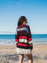 Buzo tejido con diseño de rayas horizontales en tonos marrón, azul, verde y blanco.