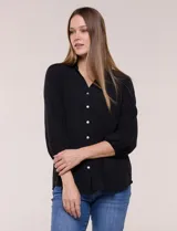 Blusa negra de silueta suelta y textura liviana, con escote en V y cuello mao. Cuenta con acceso frontal mediante abotonadura completa, detalle de alforzas verticales en el pecho y mangas tres cuartos con galón calado tipo puntilla y puños elastizados.