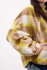 Campera bomber oversize de paño italiano con estampado en zigzag blanco y negro, cuello alto y cierre frontal con broches a presión. Tiene mangas murciélago.