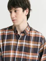 Camisa de franela de manga larga con estampado de cuadros escoceses, cuello button-down y cierre frontal con botones.