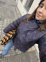 Campera acolchada impermeable color marrón oscuro con estampado a cuadros y flores azules, cuello camisero, bolsillos laterales y cierre frontal con broches a presión.