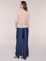 Buzo de punto fino color gris, de calce relajado, escote redondo amplio y canesú con textura acanalada. Cuenta con apliques de tachas metálicas doradas en la línea del hombro, mangas largas de hombro caído y puños y ruedo acanalados.