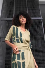 Vestido color beige con estampado abstracto en verde, confeccionado en lana, seda y algodón. Diseño cruzado con cuello en V texturizado y lazo lateral.