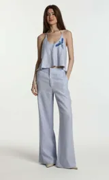 Pantalón de lino para mujer con corte de sastrería, silueta amplia de pernera recta y pinzas frontales. Presenta cintura de tiro medio-alto con trabillas y cierre frontal.