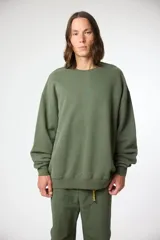 Buzo de algodón color verde oliva, con cuello redondo y un pequeño logo bordado en el pecho. Presenta un calce holgado y mangas largas con puños y ruedo acanalados.