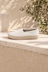Chatita de lona color beige, con diseño sin cordones tipo slip-on y suela revestida en yute trenzado.