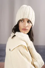 Gorro tipo beanie tejido a mano en punto canalé, confeccionado en lana fina sin teñir de color crema.