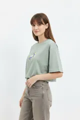 Remera cropped de algodón color verde militar, con cuello redondo y estampado central en el pecho.